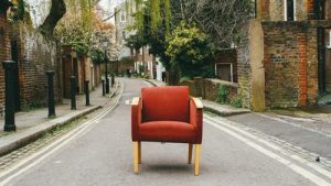 Old red chair in the street before upholsterers Edinburgh re-upholster it